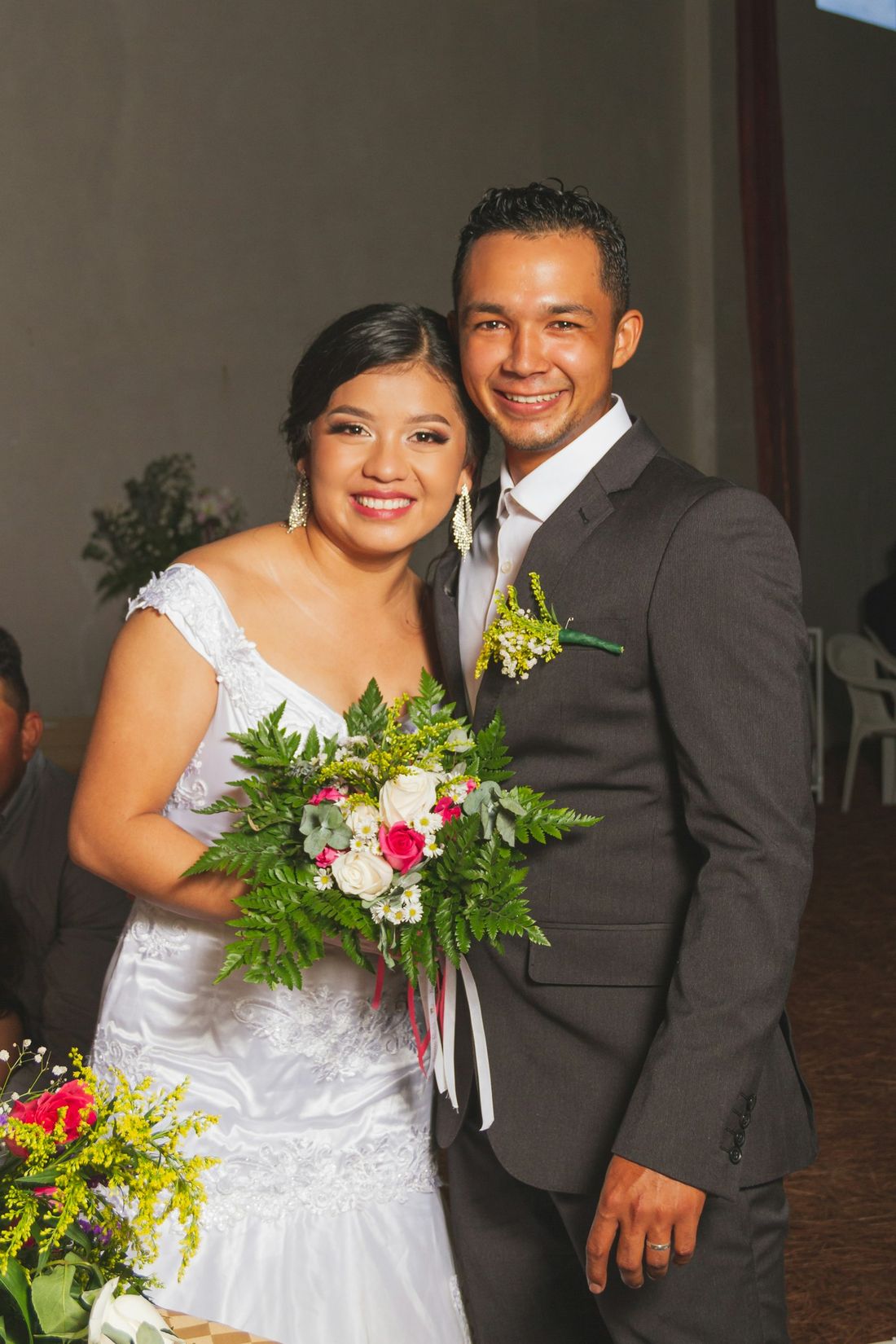A smiling newlywed couple holding a bouquet