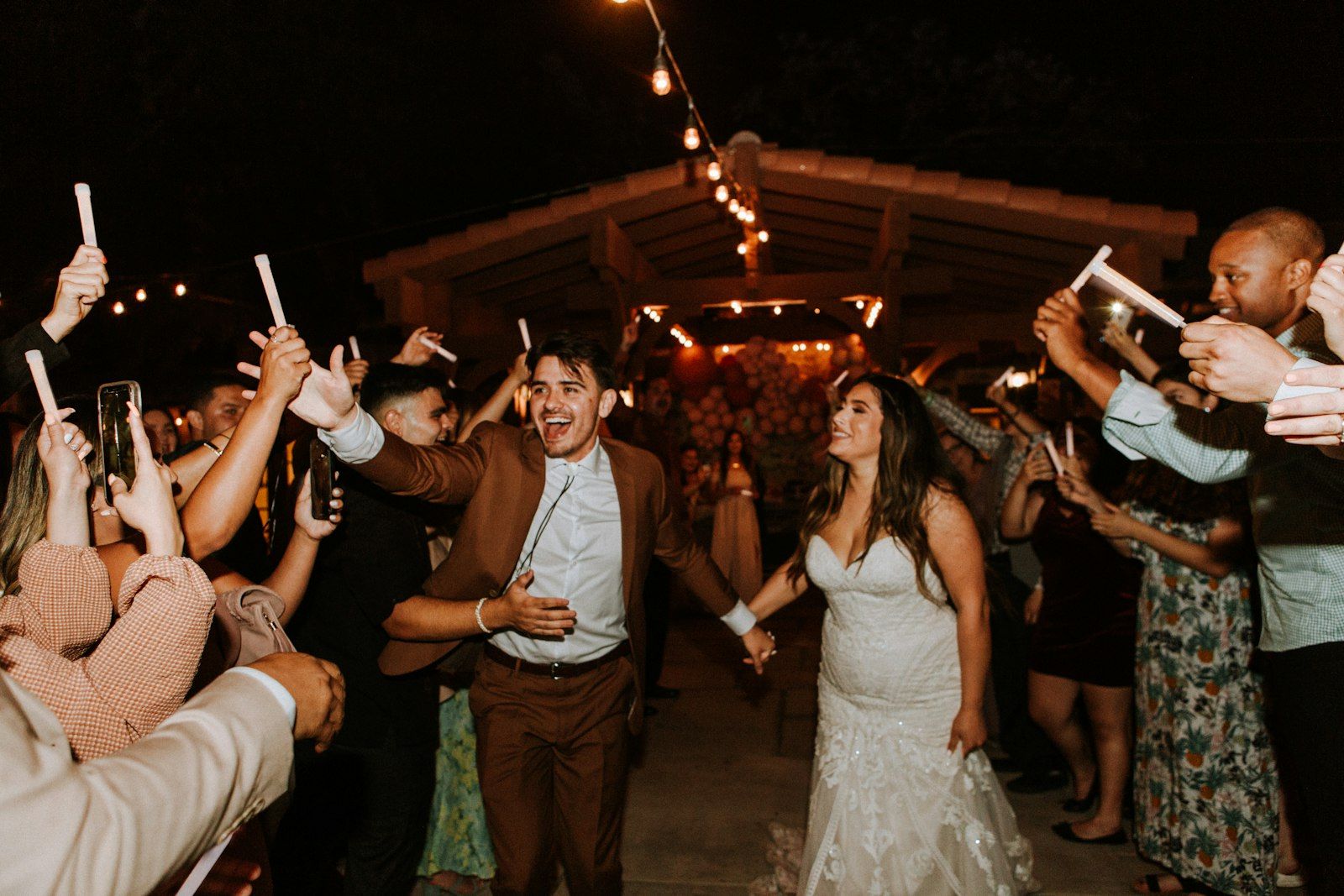 Guests holding glow sticks as the couple walks through
